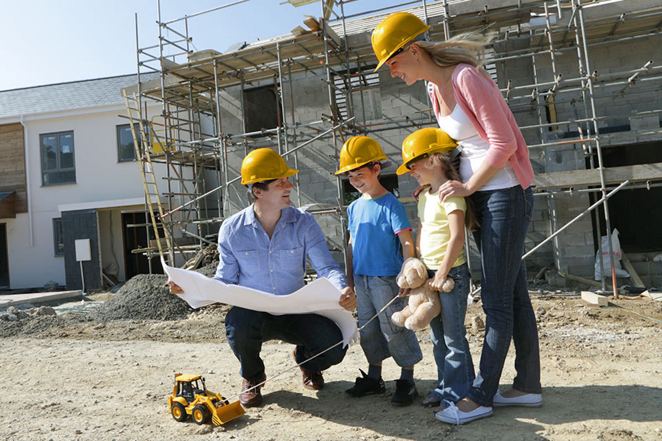 Familie mit Bauplan steht auf Baustelle