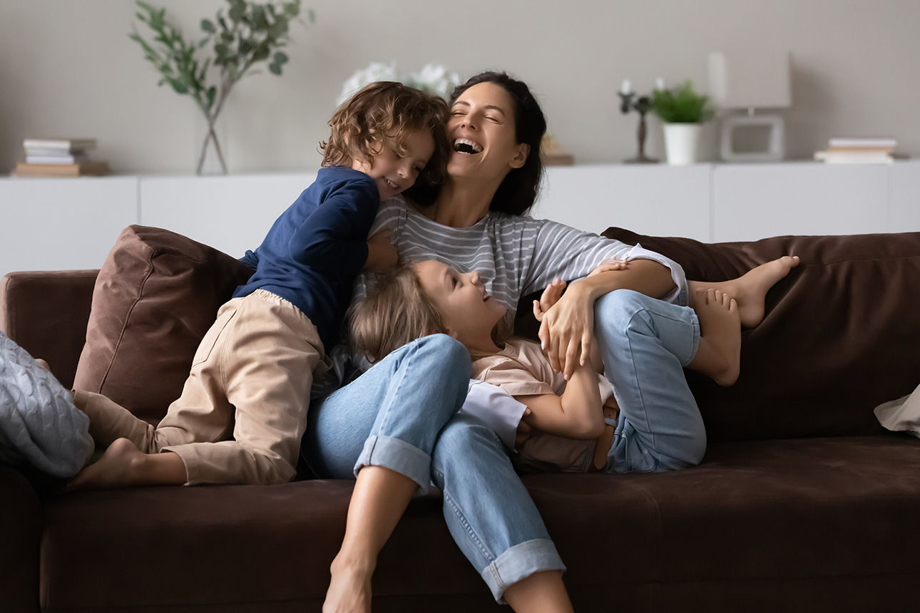 Familie sitzt lachend zusammen auf der Couch