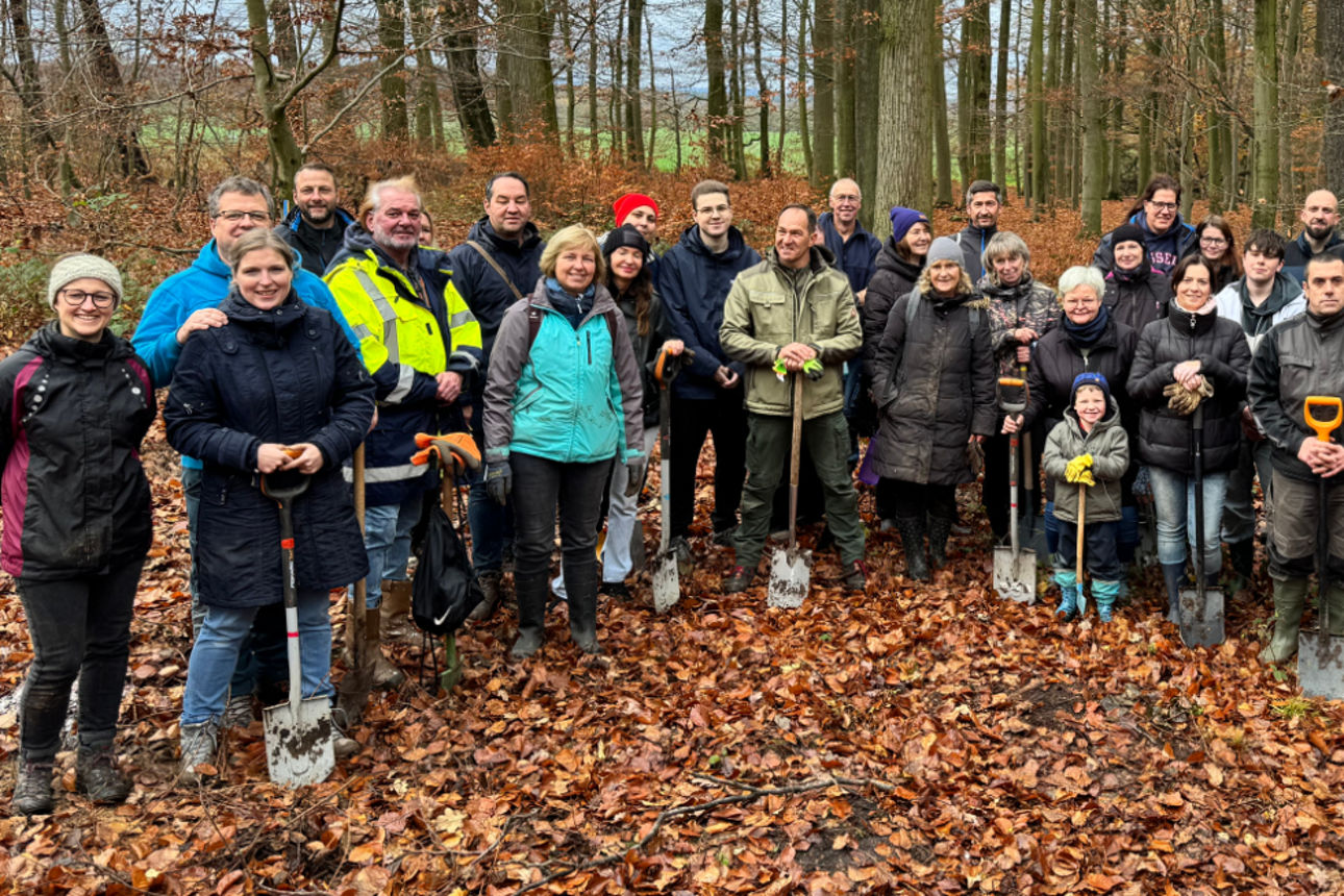 Gruppe von Helfern steht lächelnd im Wald.