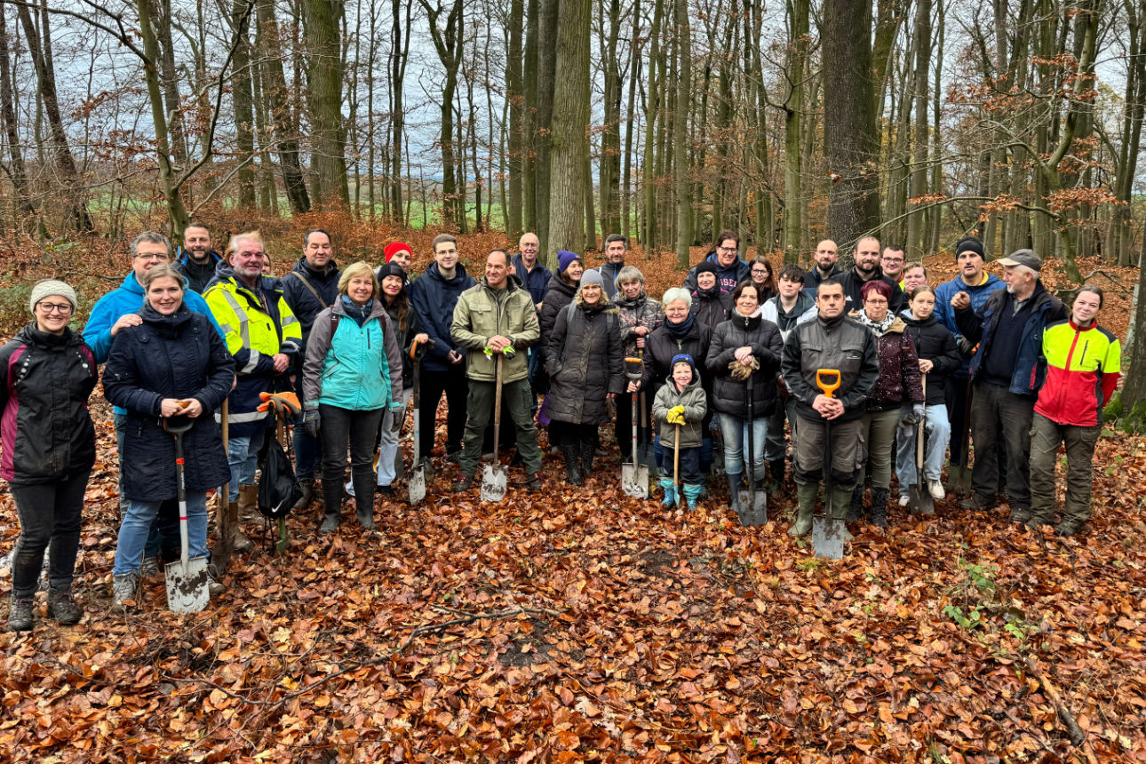 Gruppe von Helfern steht lächelnd im Wald.