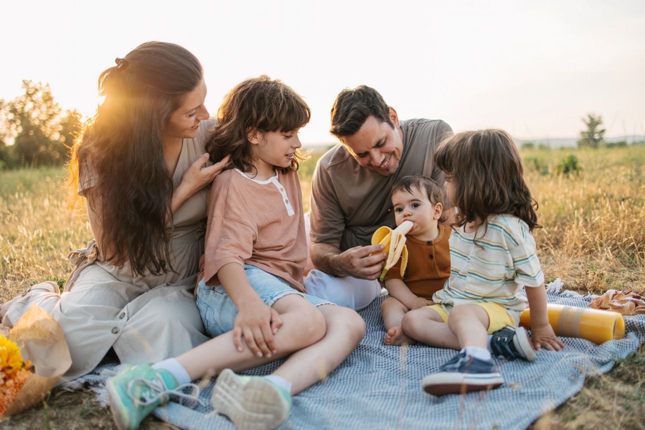 Familie sitzt während des Sonnenuntergang auf einer Picknickdecke