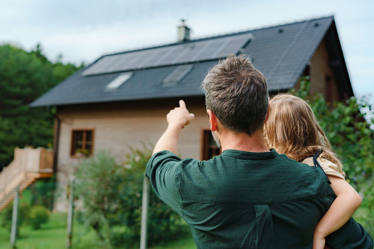 Vater zeigt seiner Tochter ein Haus – ein Symbol für frühes Bausparen für Kinder.
