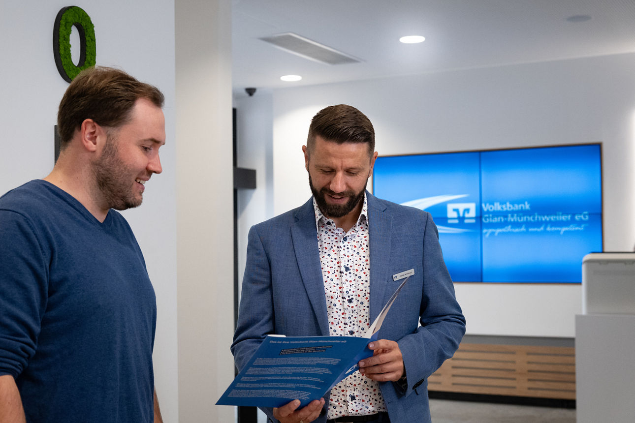 Berater zeigt einem Kunden Unterlagen in der Filiale einer Bank