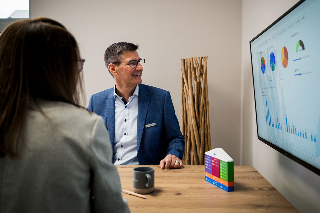 Ein Berater erklärt einer Kundin an einem Bildschirm verschiedene Diagramme