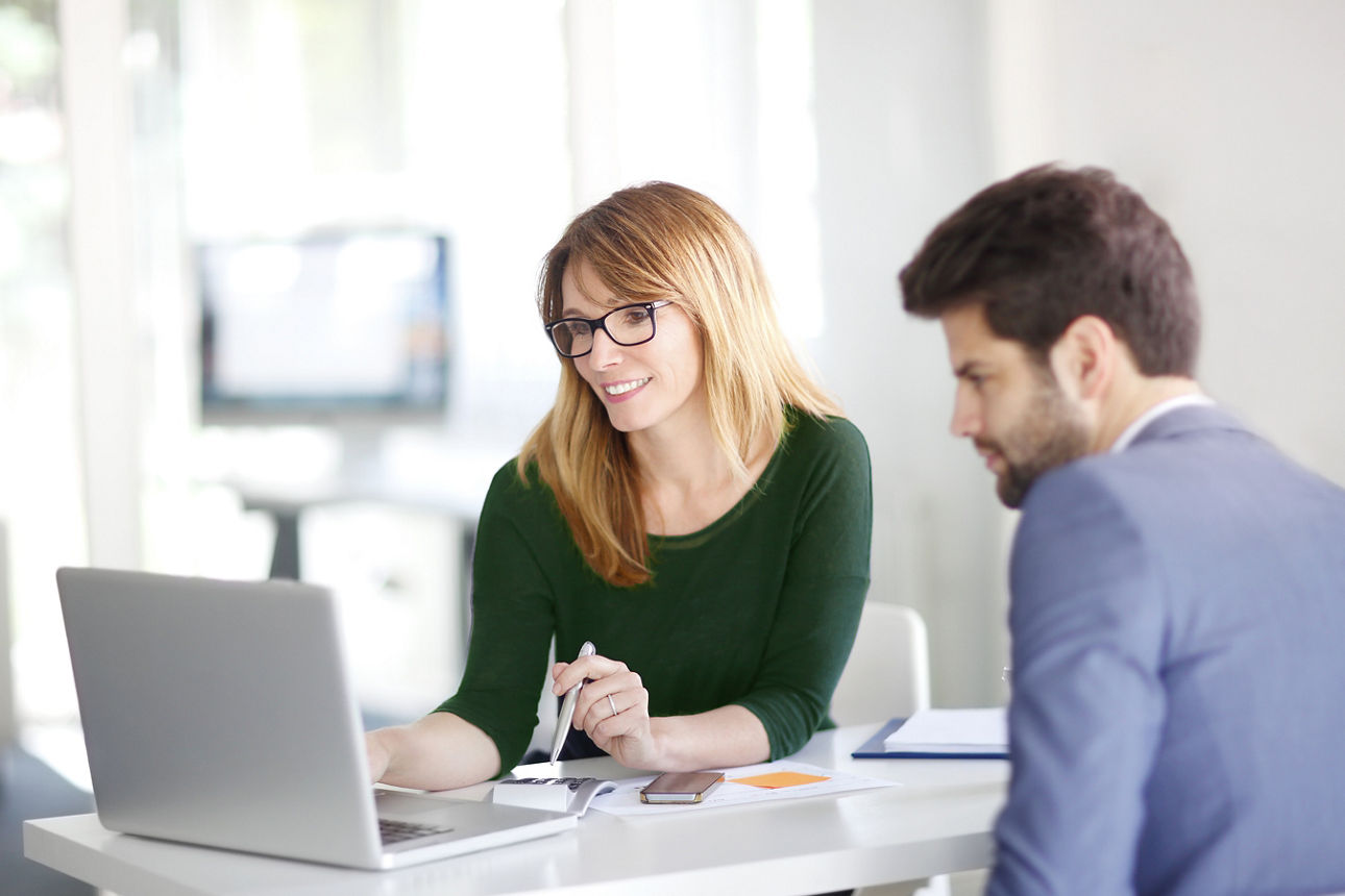 Ein Mann und eine Frau sitzen an einem Tisch in einem Beratungsgespräch.