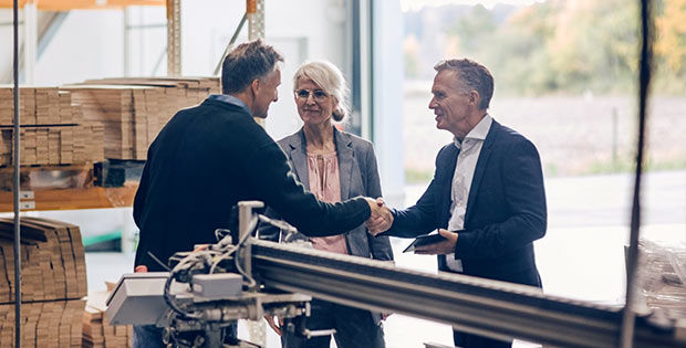 Frau mit zwei Männern im Gespräch die sich die Hand geben