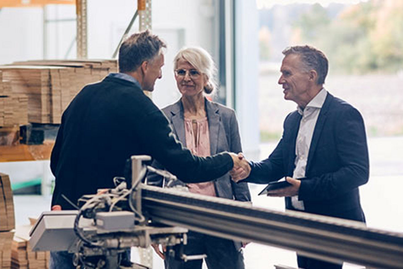 Frau mit zwei Männern im Gespräch die sich die Hand geben