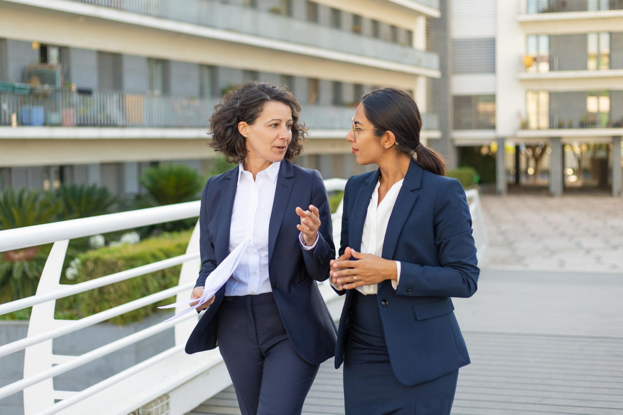 Zweit Frauen im Businesskleidung besprechen etwas draußen im Gehen