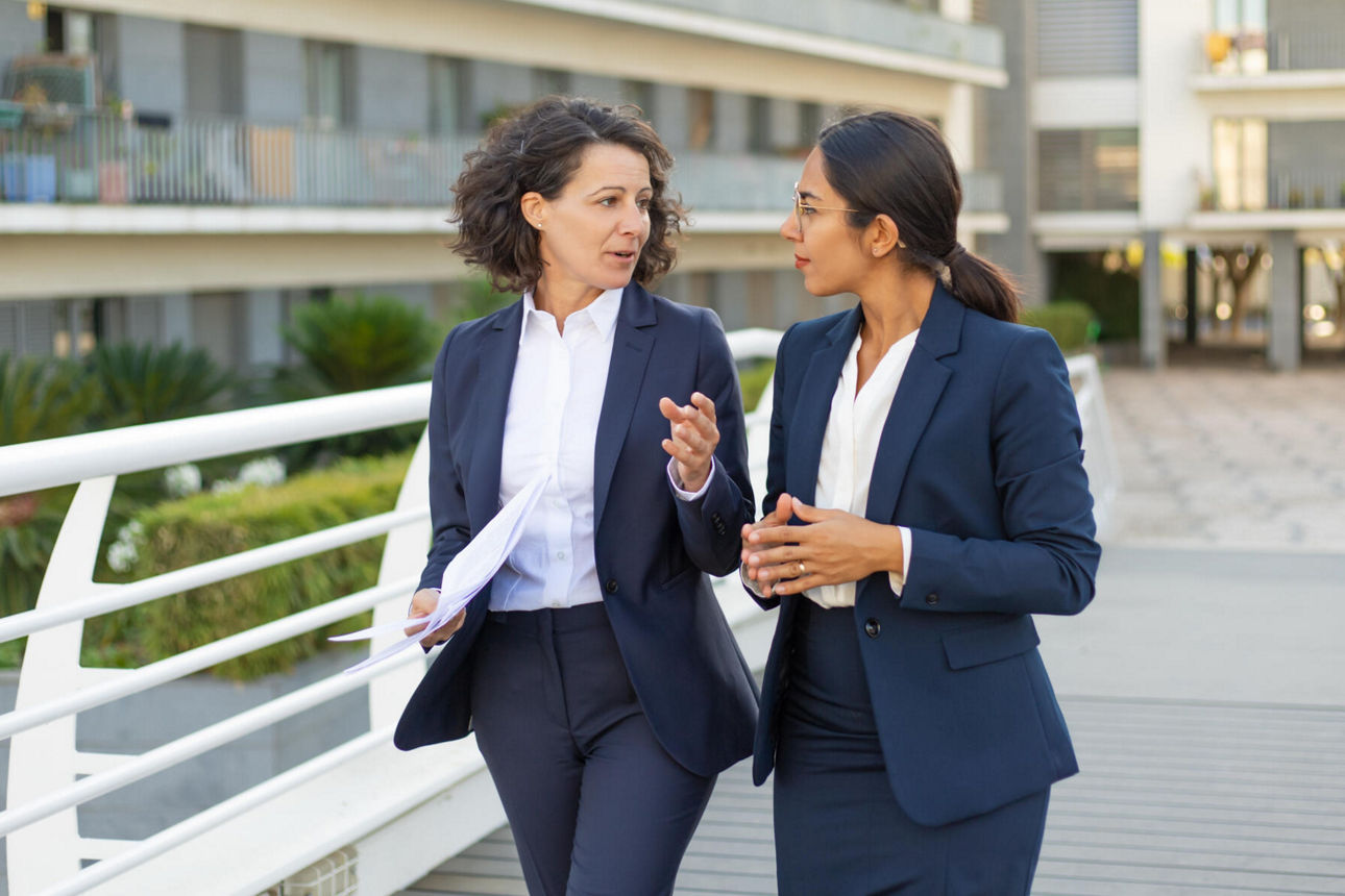 Zweit Frauen im Businesskleidung besprechen etwas draußen im Gehen
