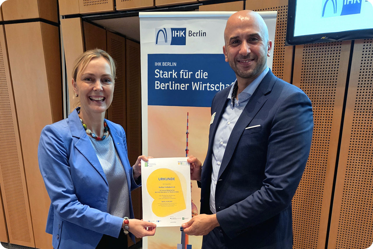 Eine Frau und ein Mann halten zusammen eine Urkunde in die Kamera