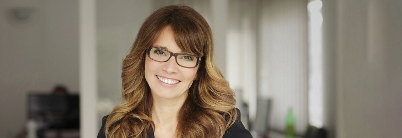 Frau mit langen Haaren und Brille lächelt