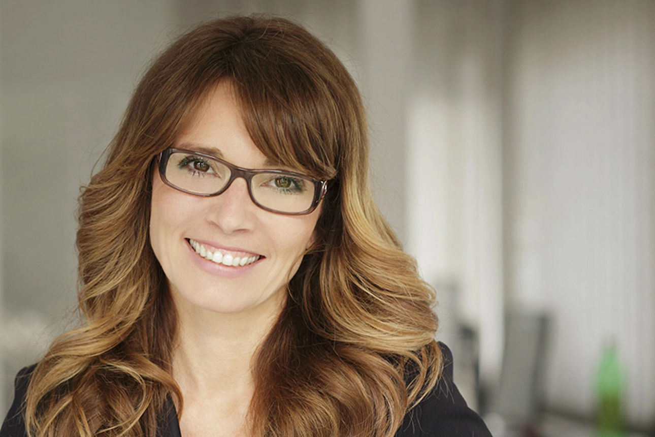 Frau mit langen Haaren und Brille lächelt