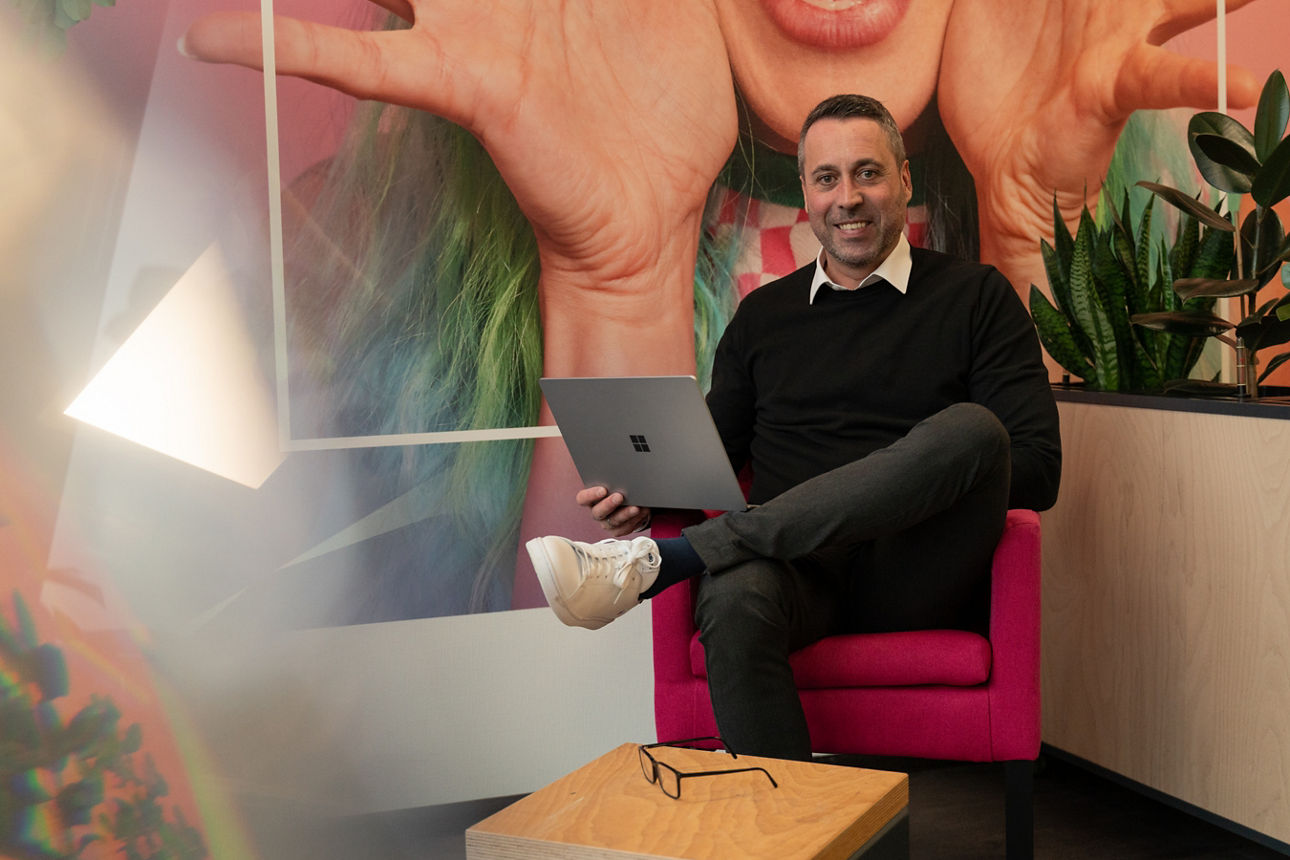 Berater in schwarzer Kleidung auf einem rosa Stuhl, einen Laptop in der Hand
