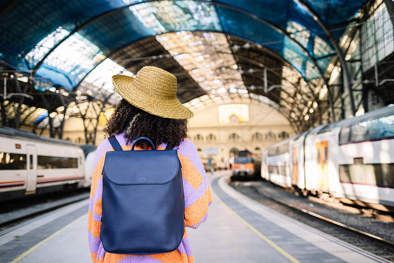 Frau mit Hut steht auf dem Bahngleis.