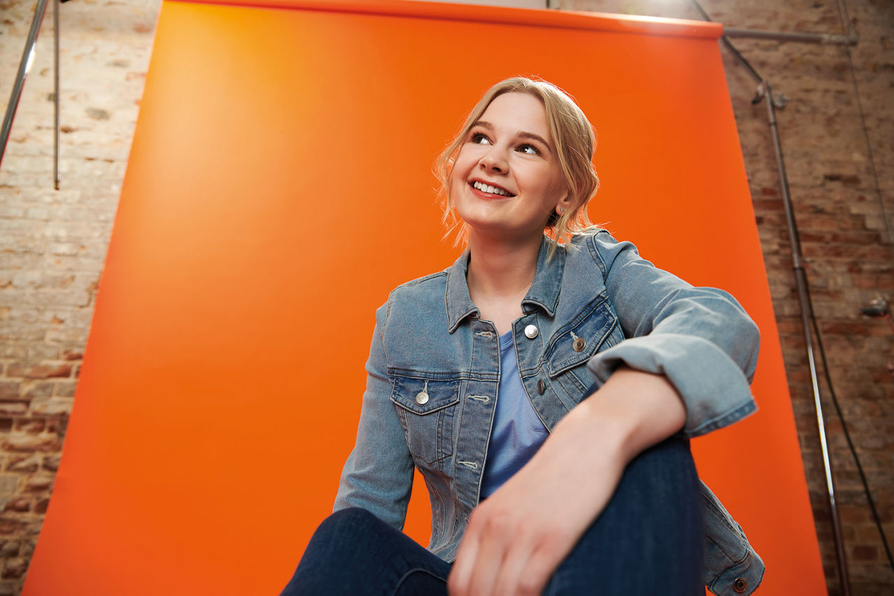 junges Mädchen vor einer orangenen Wand