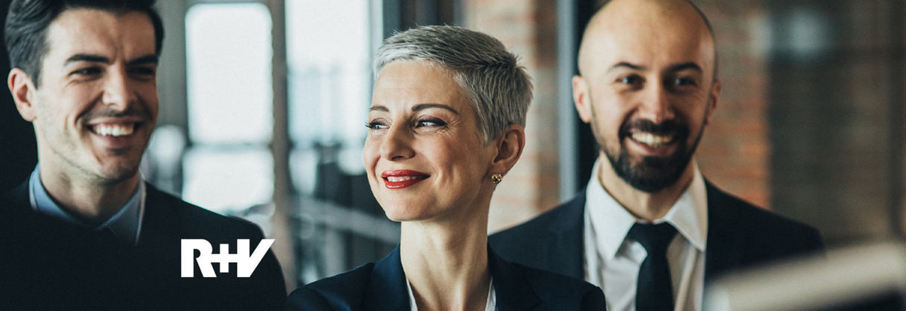 Zwei Männer und eine Frau im Business Outfit lächeln
