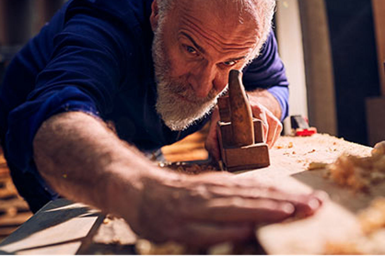 Älterer Handwerker bei der Arbeit in der Holzwerkstatt