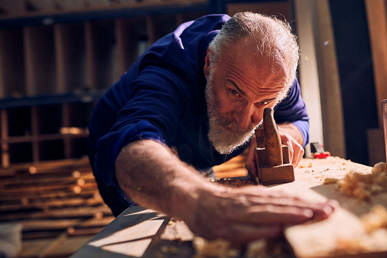 Älterer Handwerker bei der Arbeit in der Holzwerkstatt