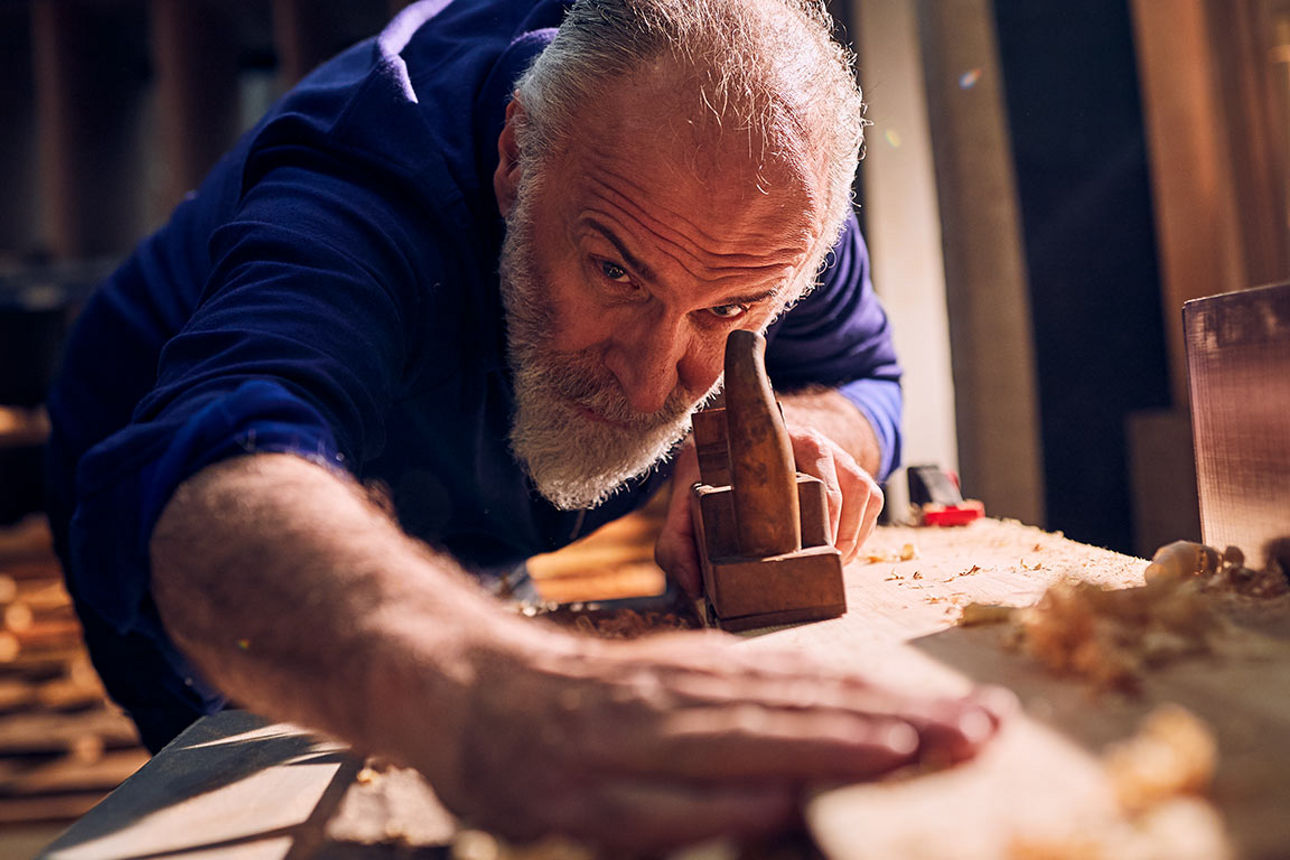 Älterer Handwerker bei der Arbeit in der Holzwerkstatt