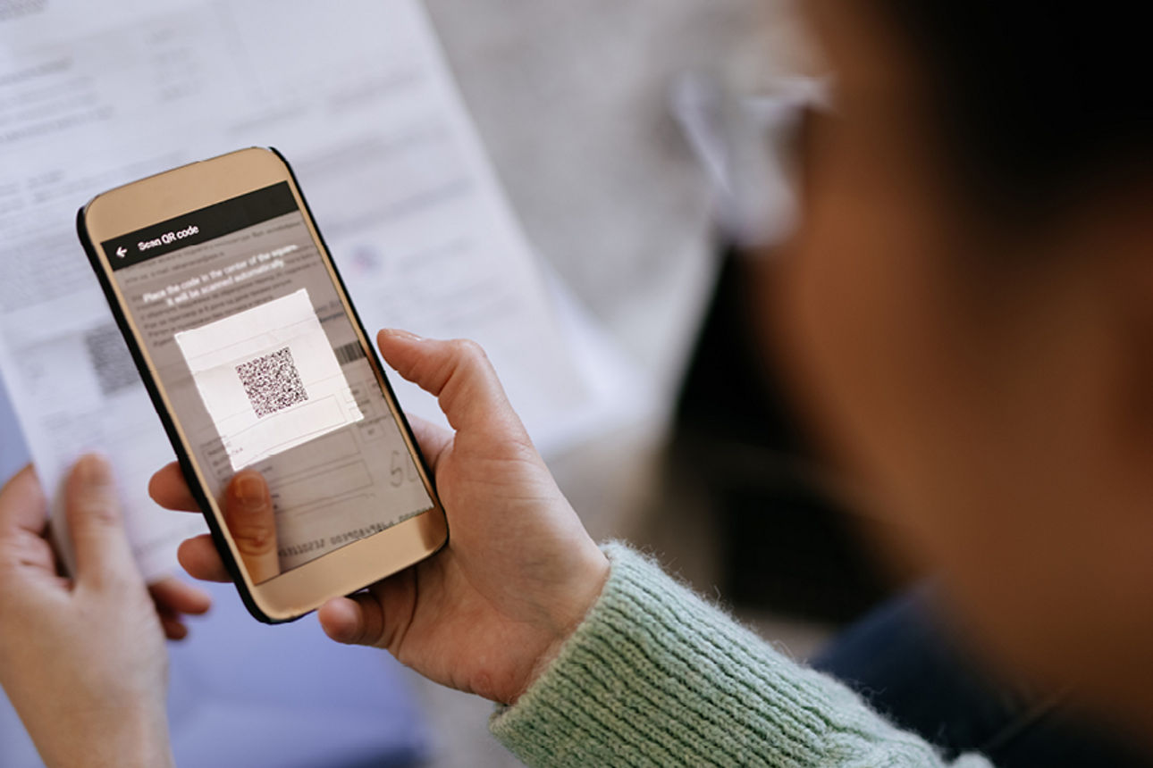 Eine Frau hält eine Handy in der Hand und scannt einen QR-Code