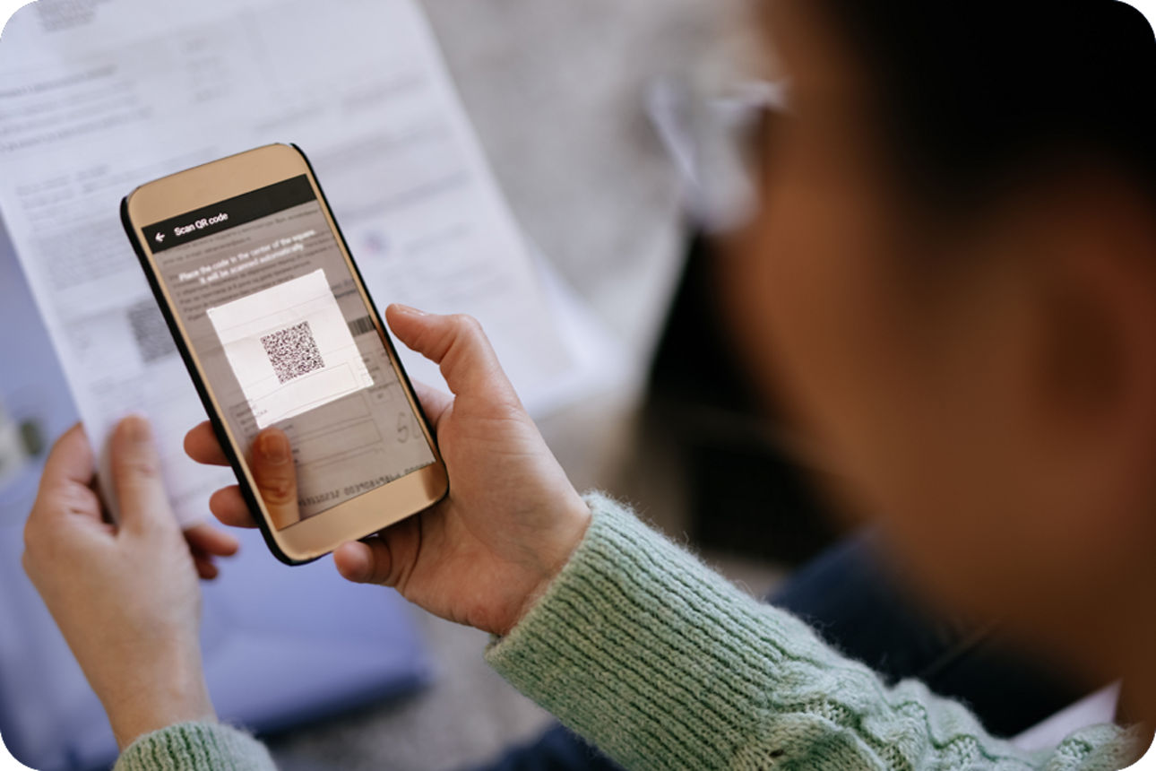 Person hält ein Handy in der Hand und scannt einen QR-Code ein.