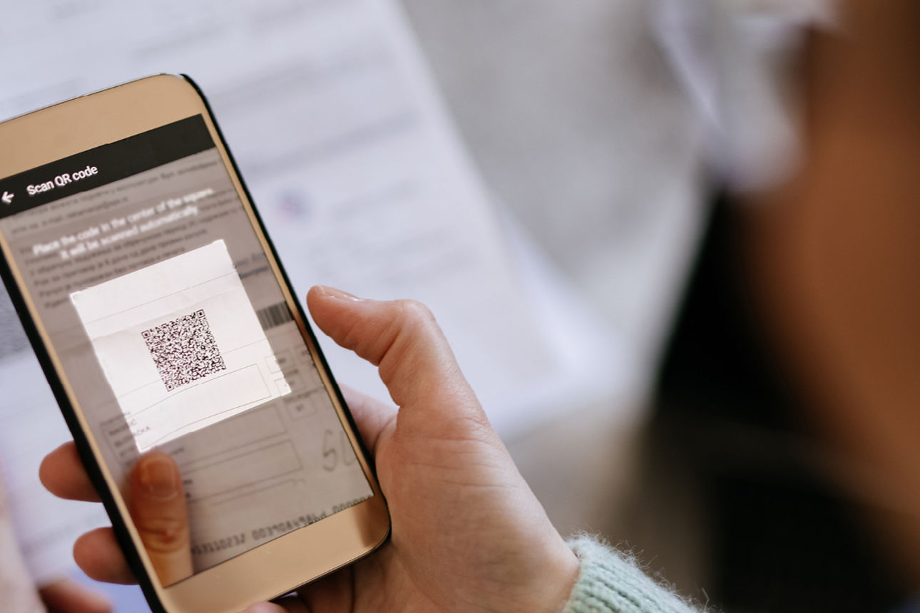 Eine Frau hält eine Handy in der Hand und scannt einen QR-Code
