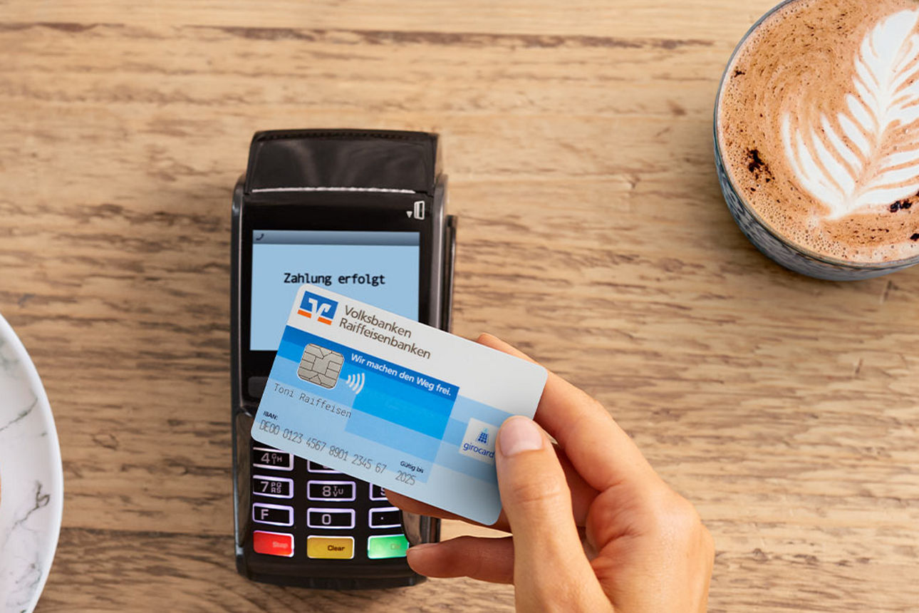 Eine Person hält eine girocard (Debitkarte) vor ein Kartenlesegerät