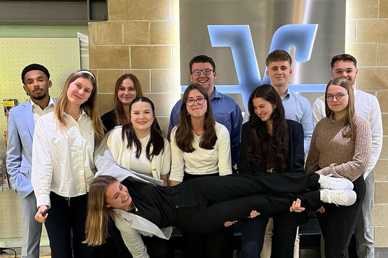 Gruppenbild unserer Azubis vor leuchtendem VR Logo