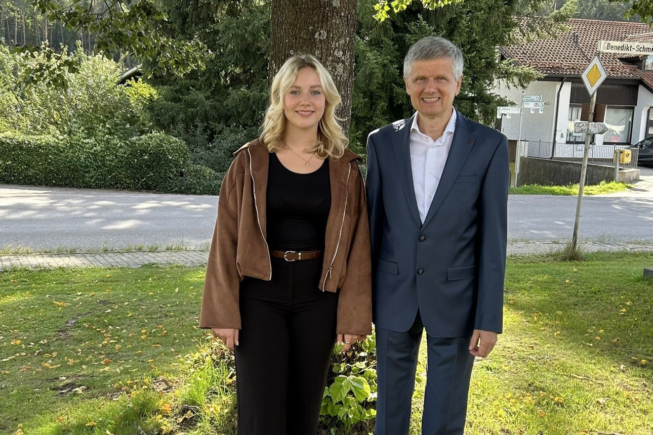 Frau und Mann stehen nebeneinander auf einer Wiese in einem begrünten Außenbereich.