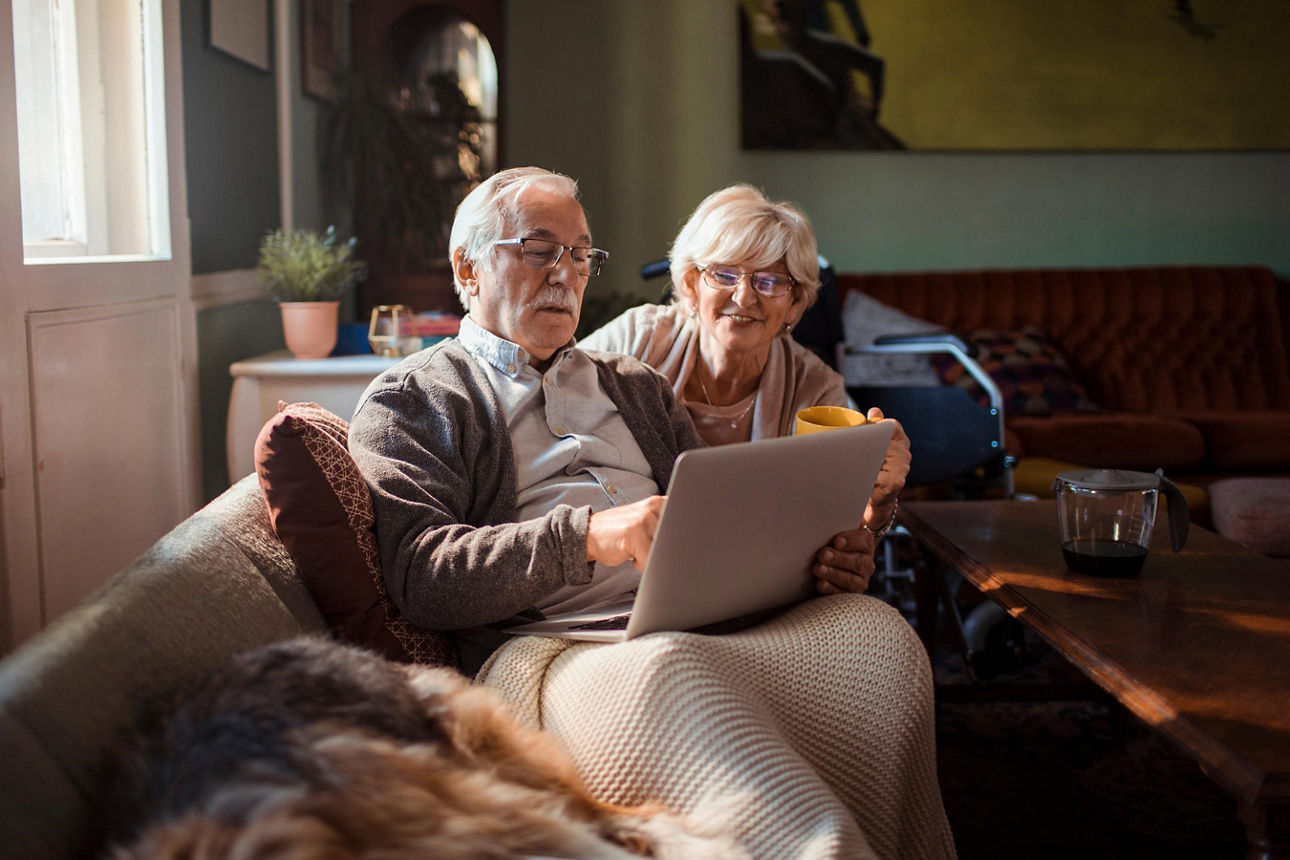 Älteres Paar schaut auf der Couch in einen Laptop