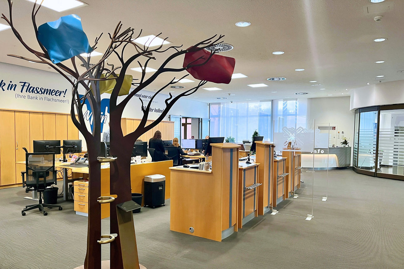 Drei Männer in der Mitte steht der Jublilar mit einem Blumenstrauß