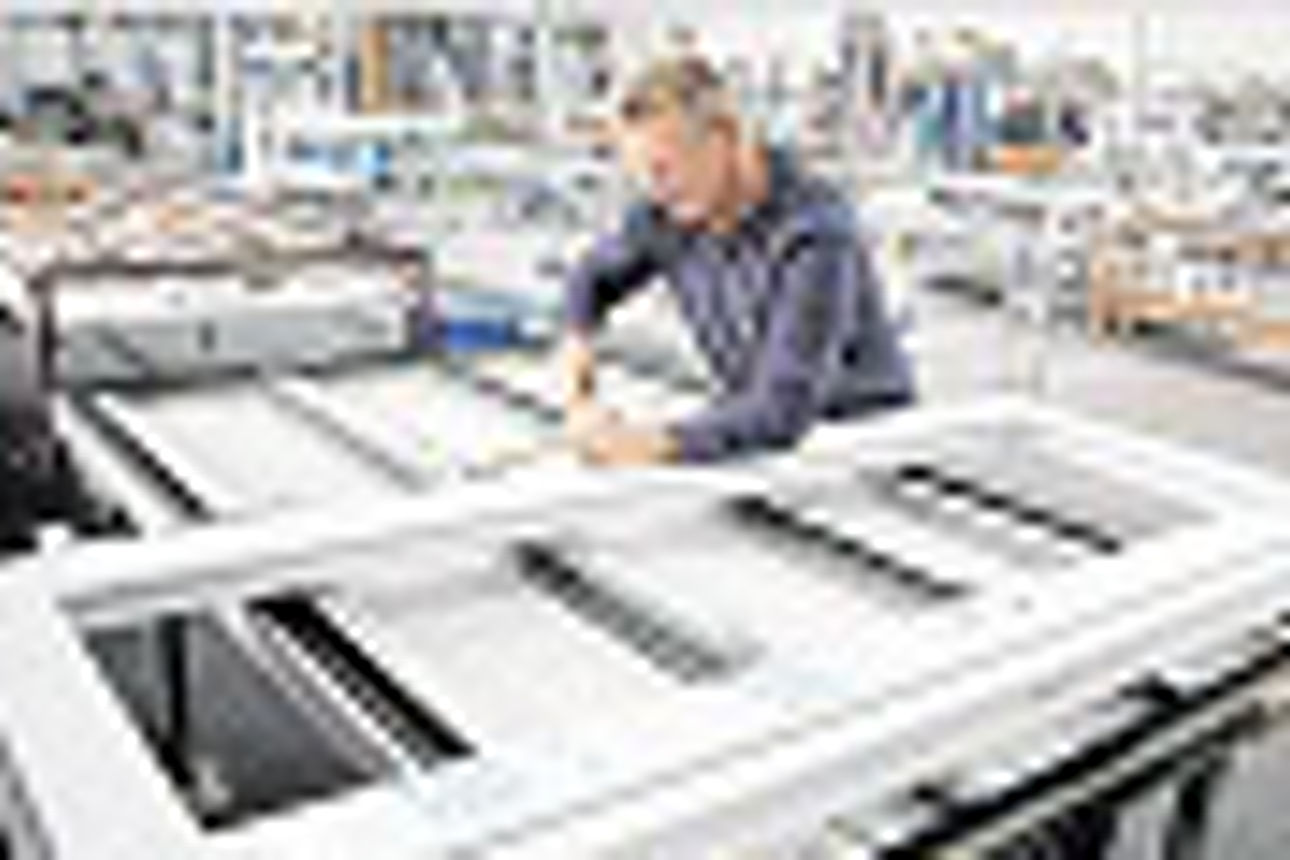 Ein Mann arbeitet an einem PVC-Türrahmen auf einer Werkbank in einer Fabrik