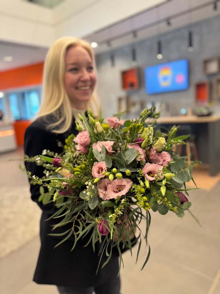 Eine Frau hält lächelnd einen großen Blumenstrauß in den Händen.
