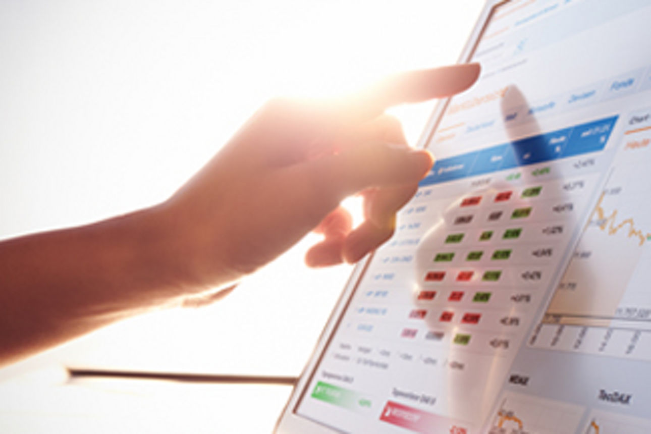 Eine Hand deutet auf einen Laptop mit Börsencharts