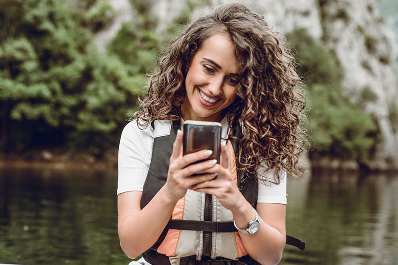 Frau in einem Kajak mit Smartphone