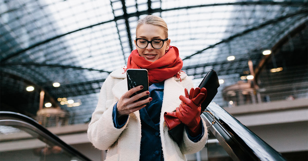 Frau mit Handy auf Rolltreppe