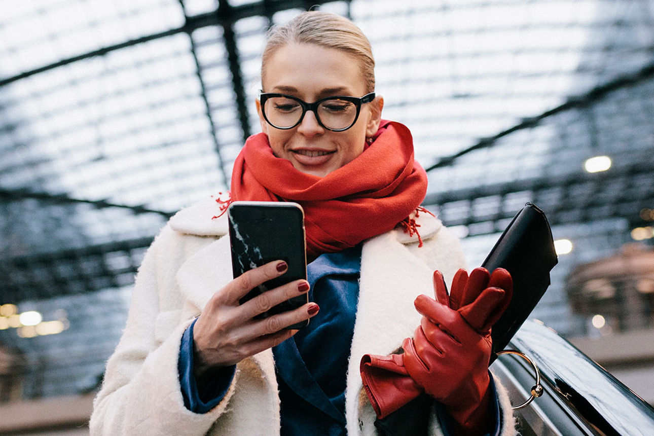 Frau auf Rolltreppe schaut in ihr  Smartphone