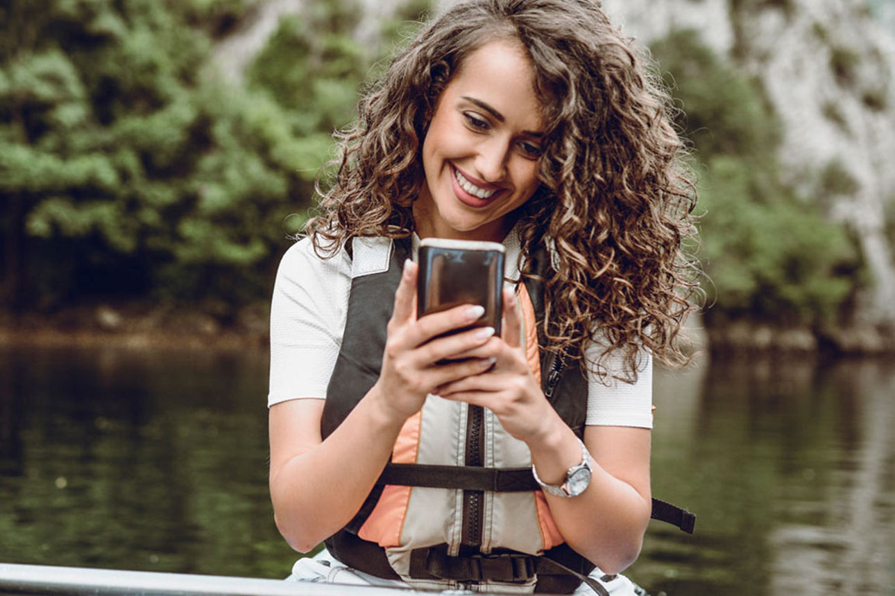Junge Frau mit Smartphone beim Paddeln