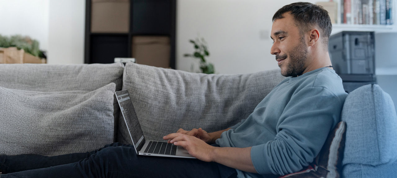 Junger Mann am Laptop auf dem Sofa