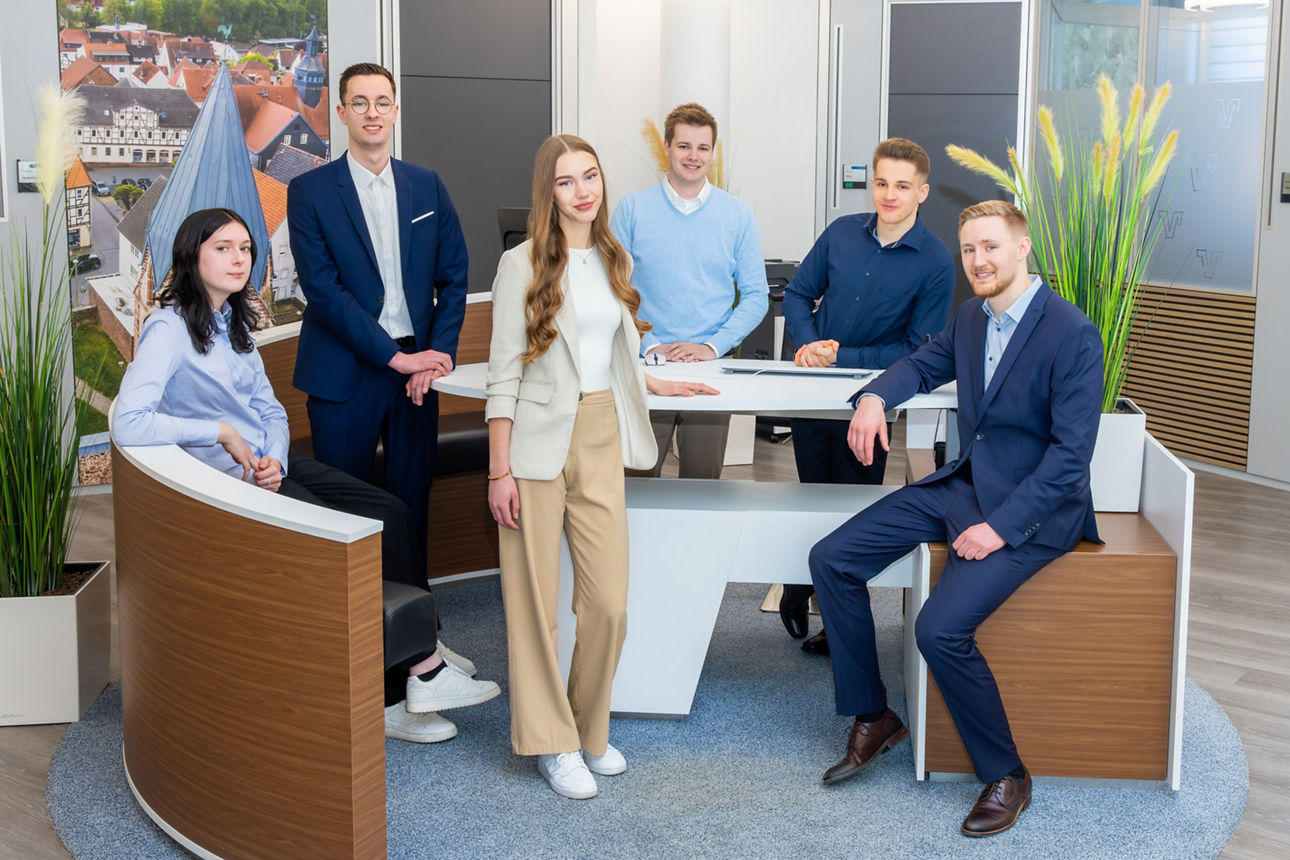 Zwei junge Auszubildende lächelt und winkt freundlich in die Kamera.