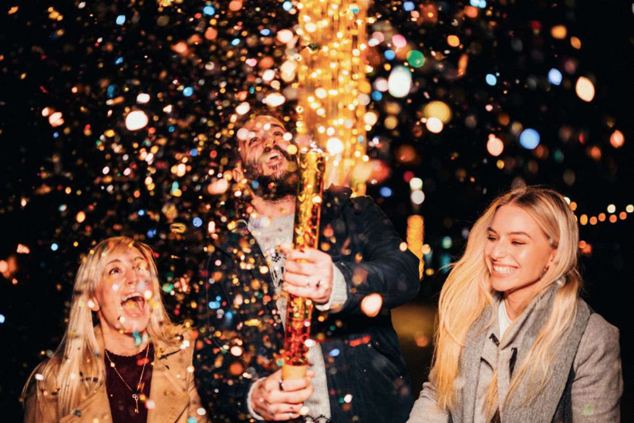 Konfetti regnet auf drei Personen.