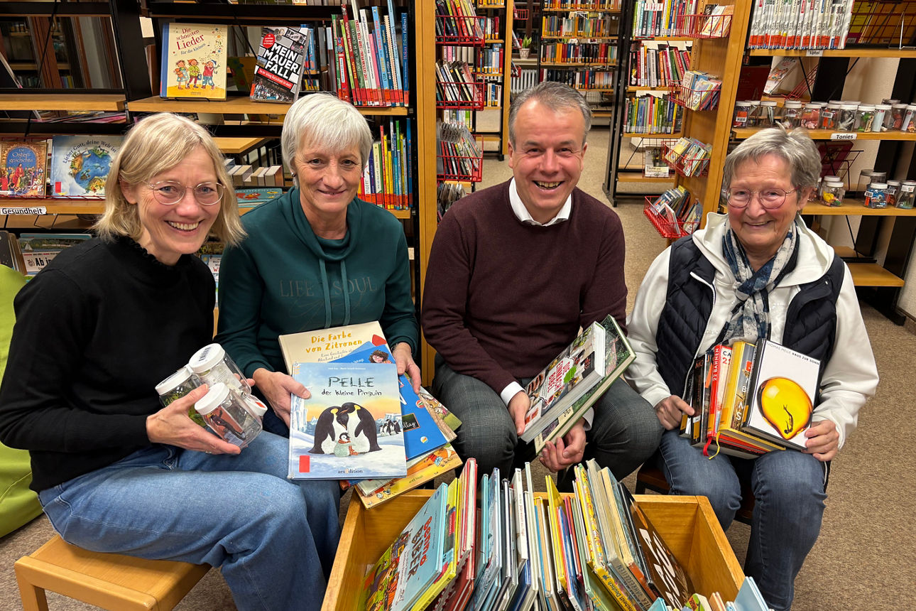 Menschen sitzem in der Bücherei und halten Bücher in der Hand.