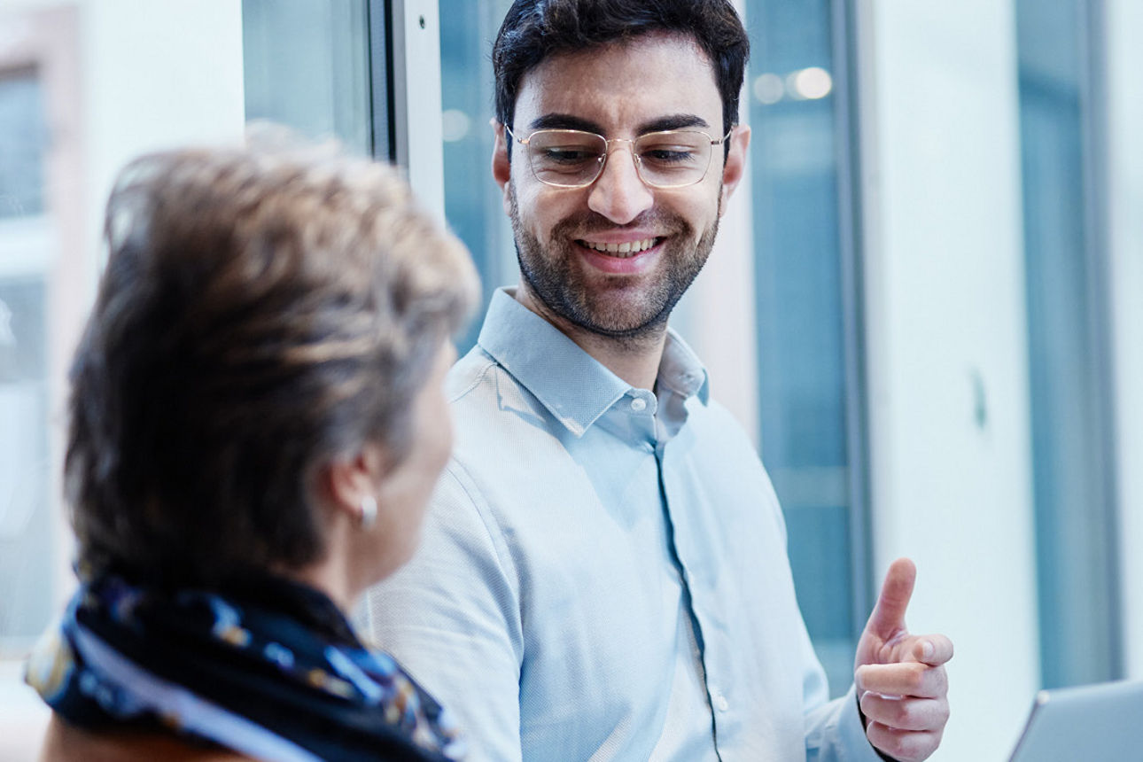 Ein Mann mit Notebook unterhält sich mit einer Frau