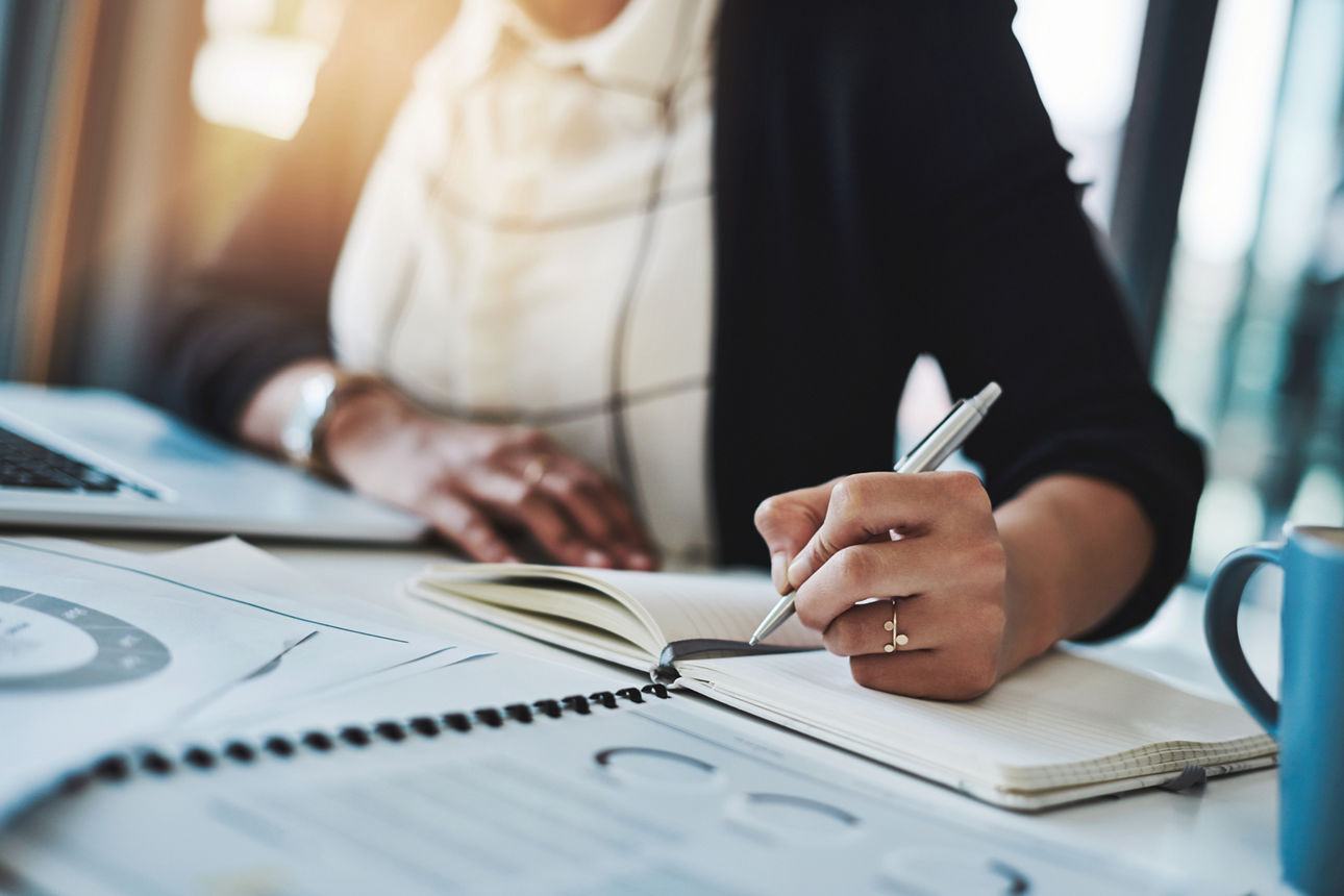 Businessplan Eine Geschäftsfrau macht Notizen an ihrem Schreibtisch – Nahaufnahme in einem modernen Büro.