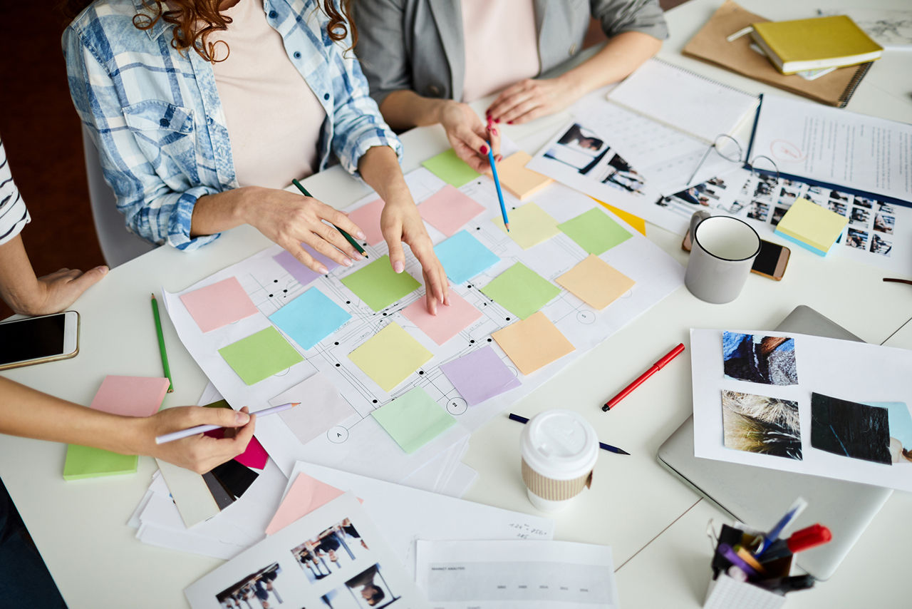 Menschen sitzen am Tisch und kleben Postit