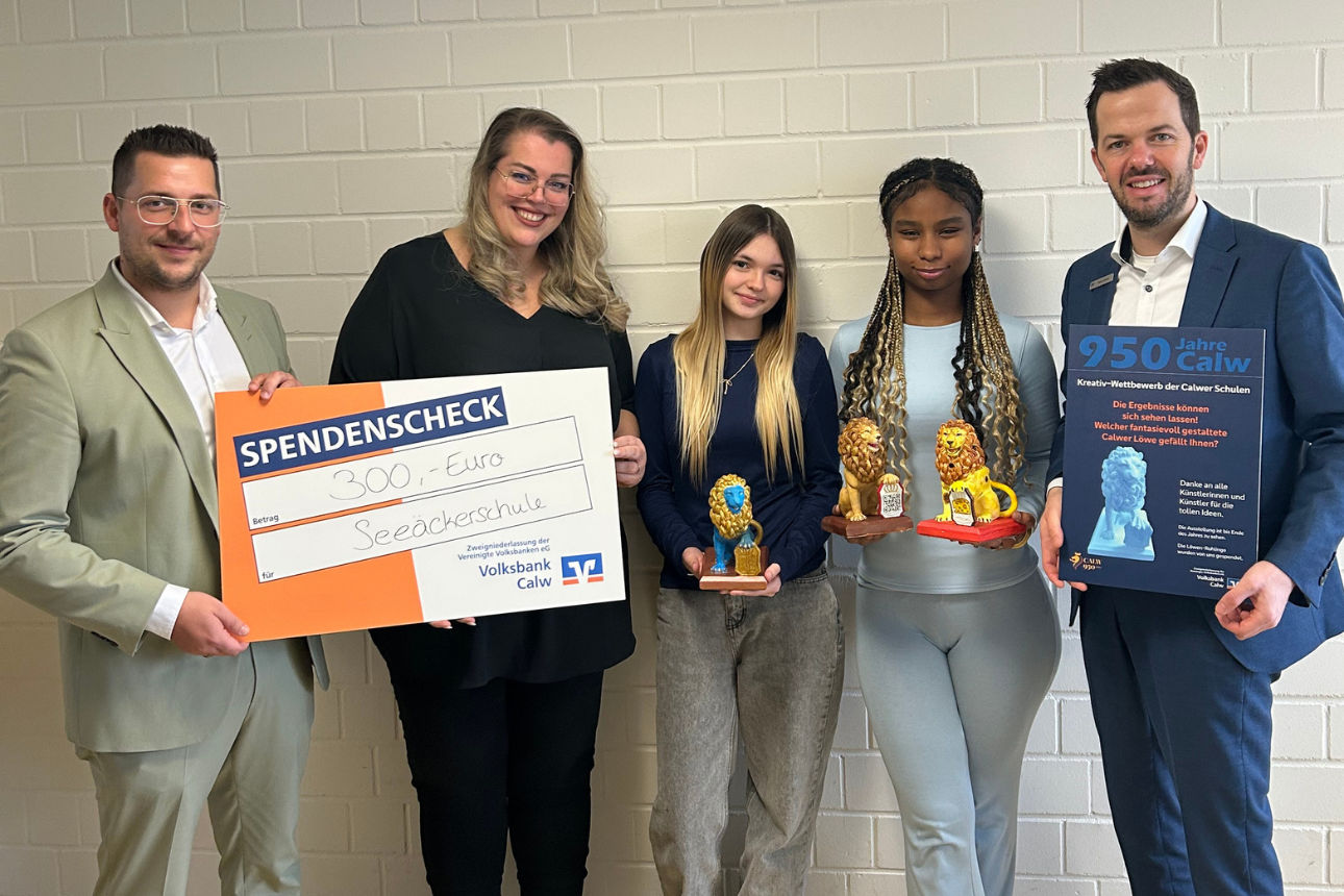 Drei Erwachsene und zwei Jugendliche stehen vor einer Wand und halten einen Spendenscheck sowie farbige Löwenfiguren.