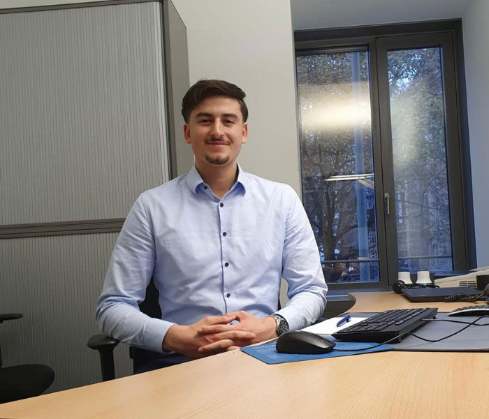 Bild von dualem Student Can im Büro am Schreibtisch