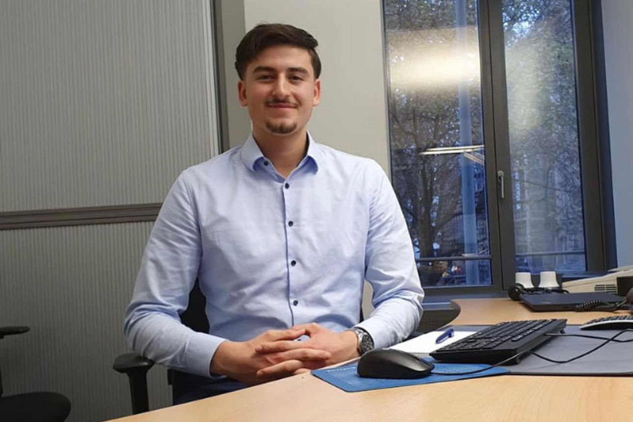 Bild von dualem Student Can im Büro am Schreibtisch