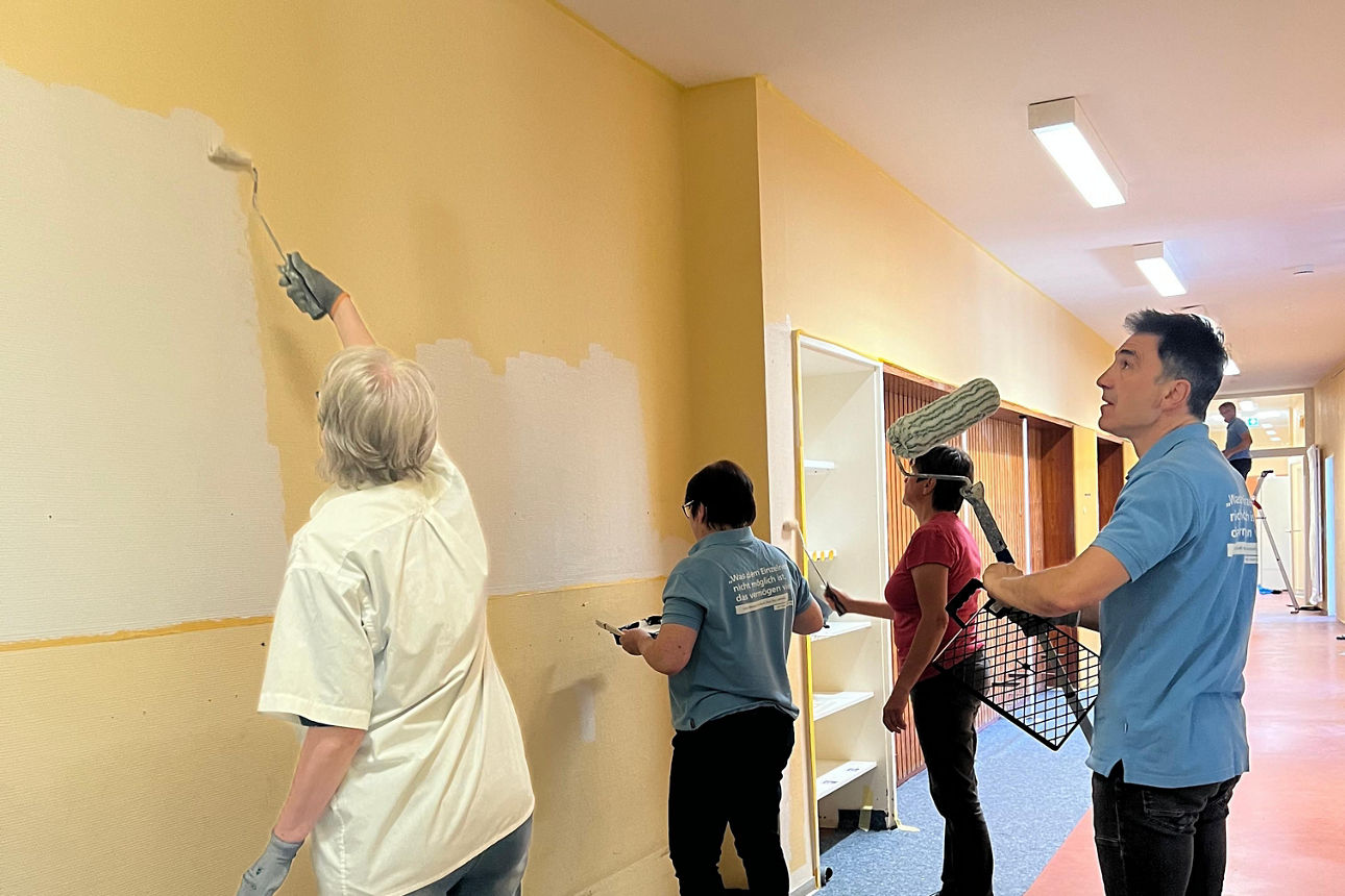 Mehrere Leute streichen eine Wand