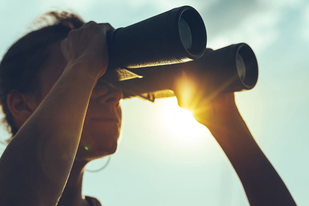 Frau schaut durch Fernglas
